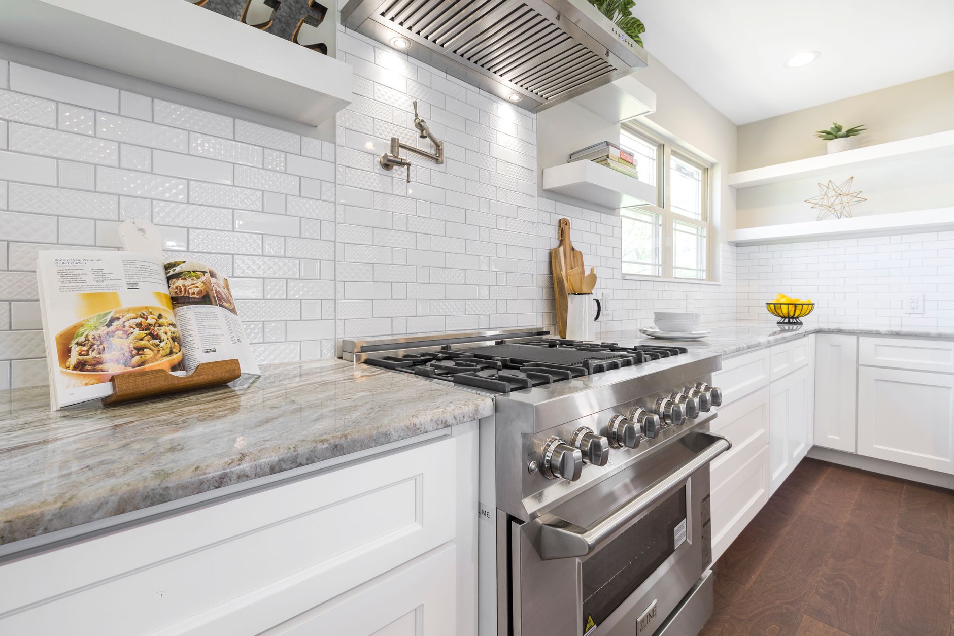 Sleek kitchen interior featuring a stainless steel gas stove, marble countertops, and open shelving in Rancho Cucamonga, CA